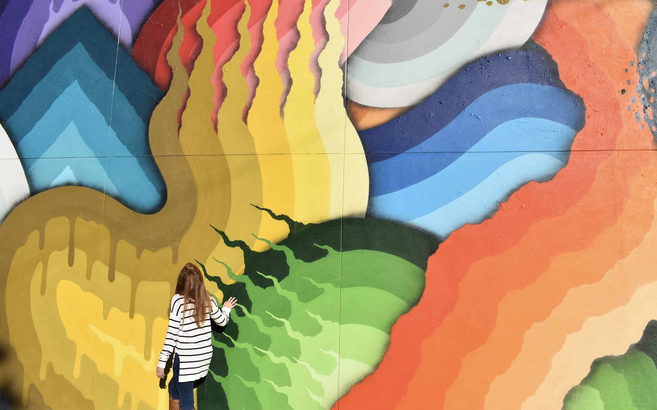 A young woman stands in front of a mural wall in St. Petersburg, Florida.