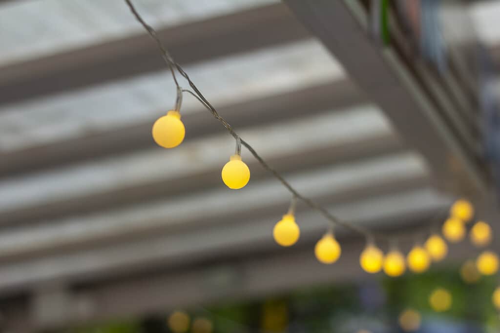 Garland.Small yellow light bulbs hang under the roof of the gazebo.