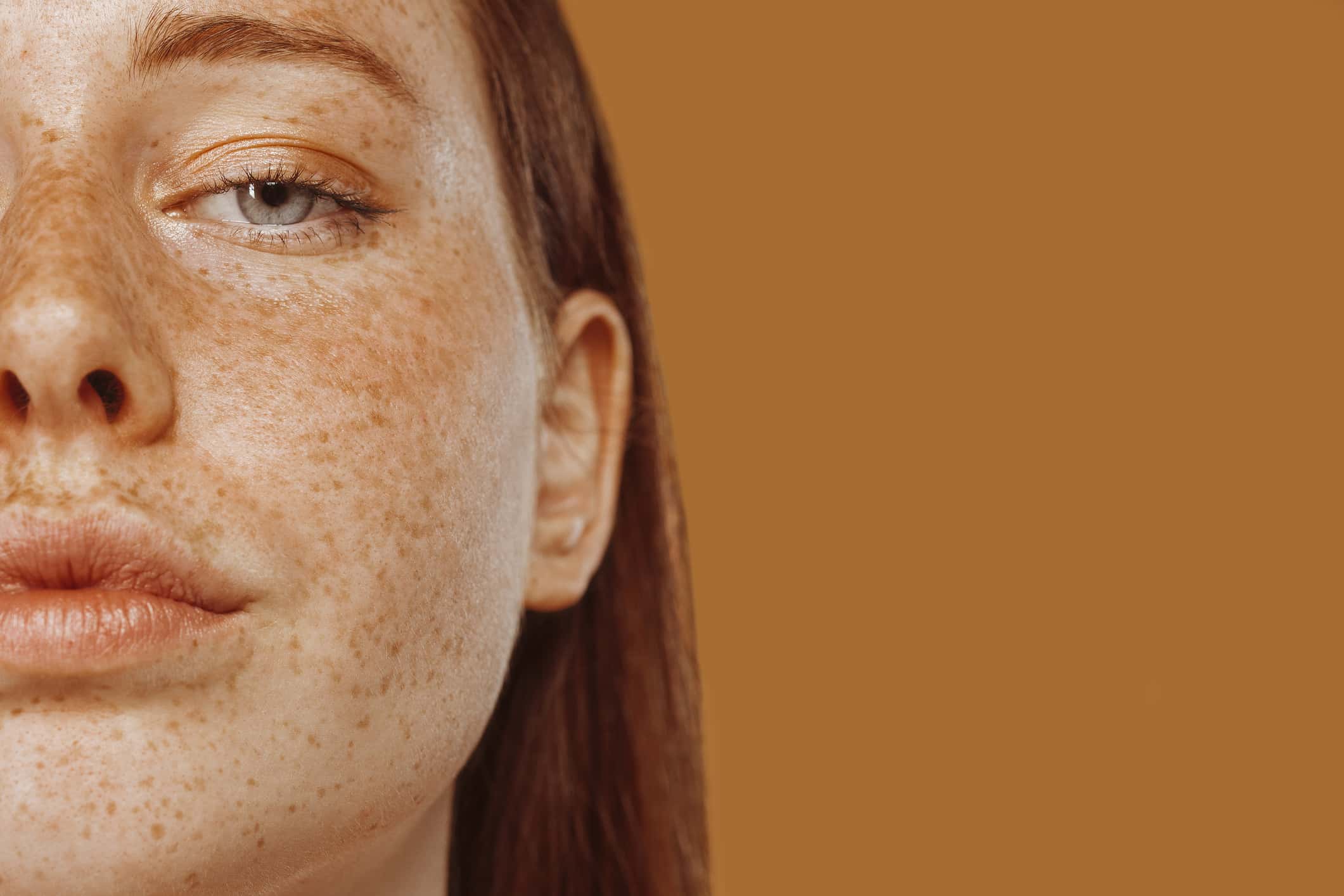Close-up portrait of half face of a red-haired girl with freckle