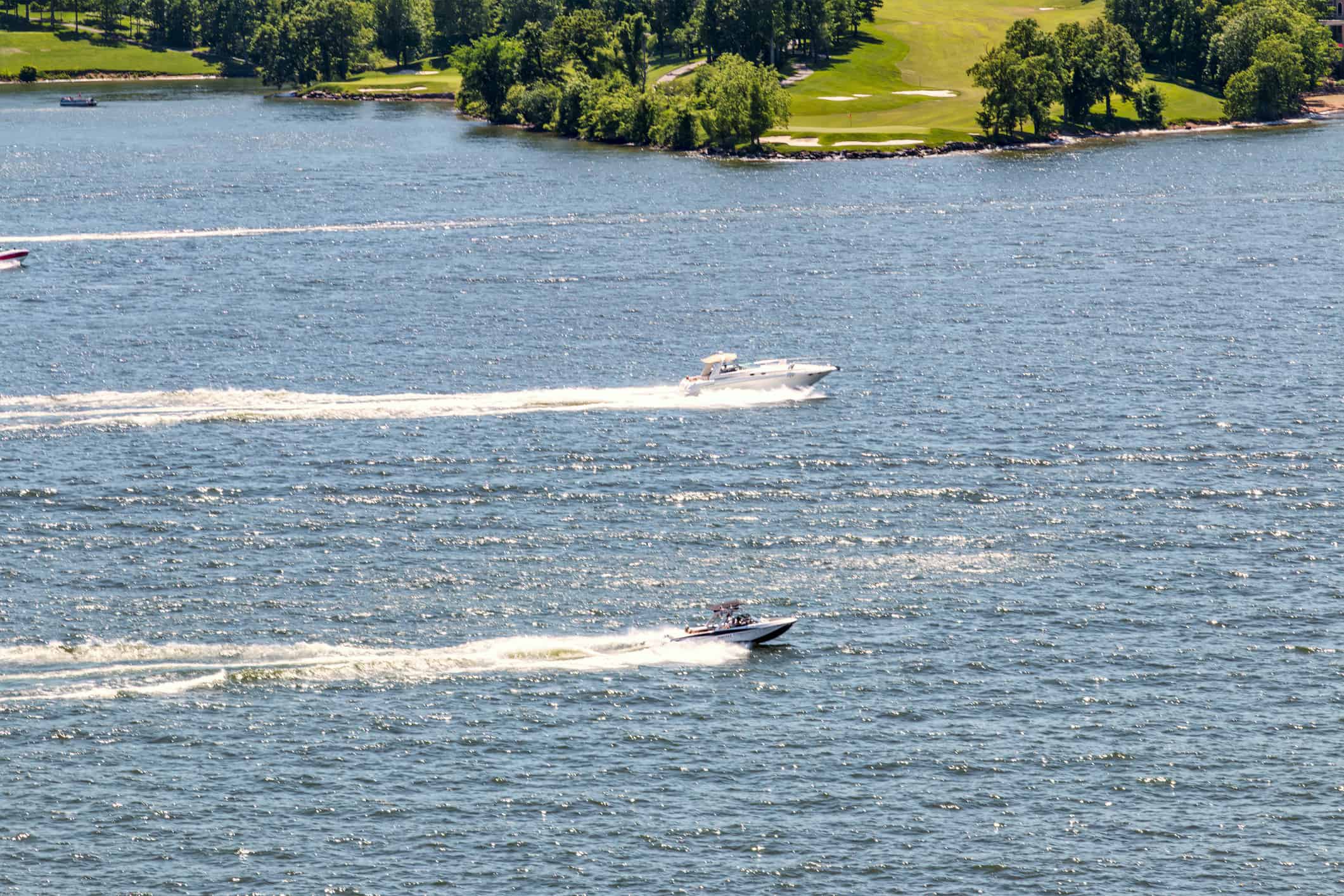 Speed boats in full throttle in Lake of Ozark and the golf course in the background, Missouri, USA.