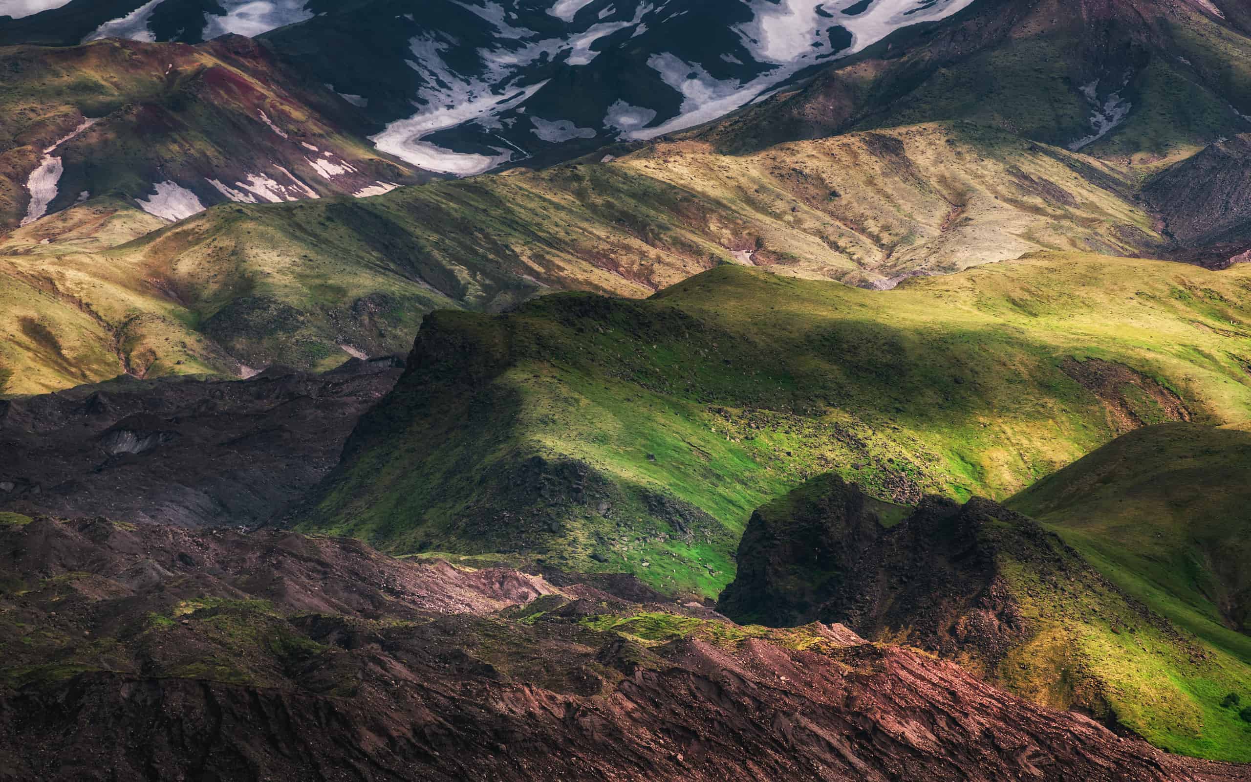 Green grass and snow on the rocks of Tolbachik volcano, Kamchatka, Russia.