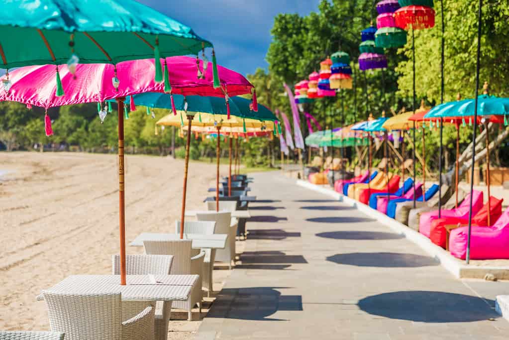 Cafe with colorful balinese umbrellas at tropical beach in Bali, Nusa Dua. Beach club restaurant