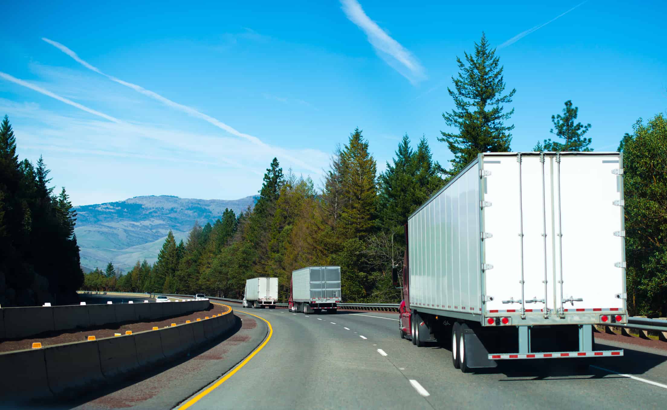 Convoy Semi trucks dry van trailers winding highway