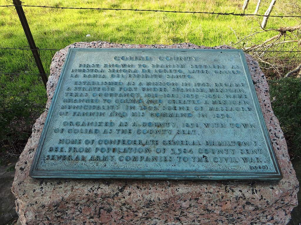Marker in Goliad County, Texas marking the history of the Weathered historic marker for Goliad County in Texas, detailing the movement of the ission Nuestra Señora along the Guadalupe River.