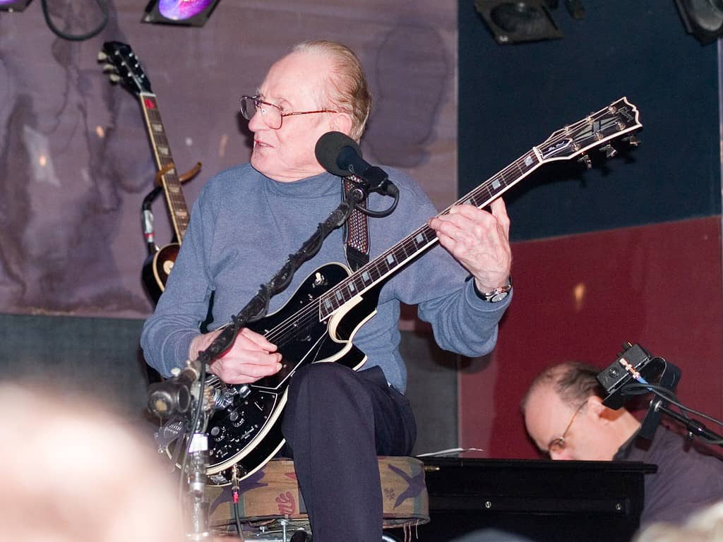 Legendary guitarist Les Paul on stage holding an electric guitar