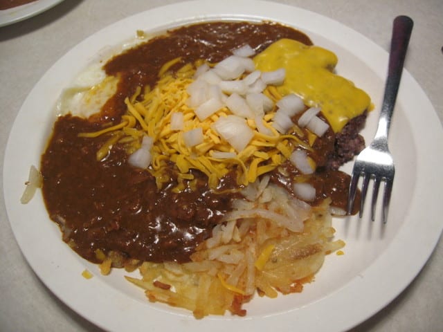 Slinger is made with eggs, hamburger patties, chili, cheese, hash browns, onions, and hot sauce. 