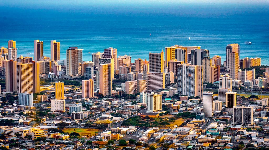 Cityscape of Honolulu city and Waikiki beach with blue ocean and light reflection from sunset sky to buildings from Ualaka’a lookout on Tantalus mountain in Honolulu, Oahu, Hawaii USA