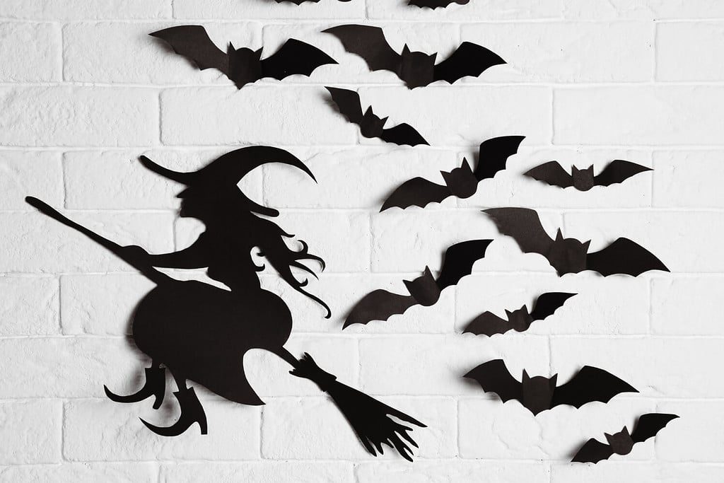 Paper bats and witch cutout on brick wall. Halloween decor
