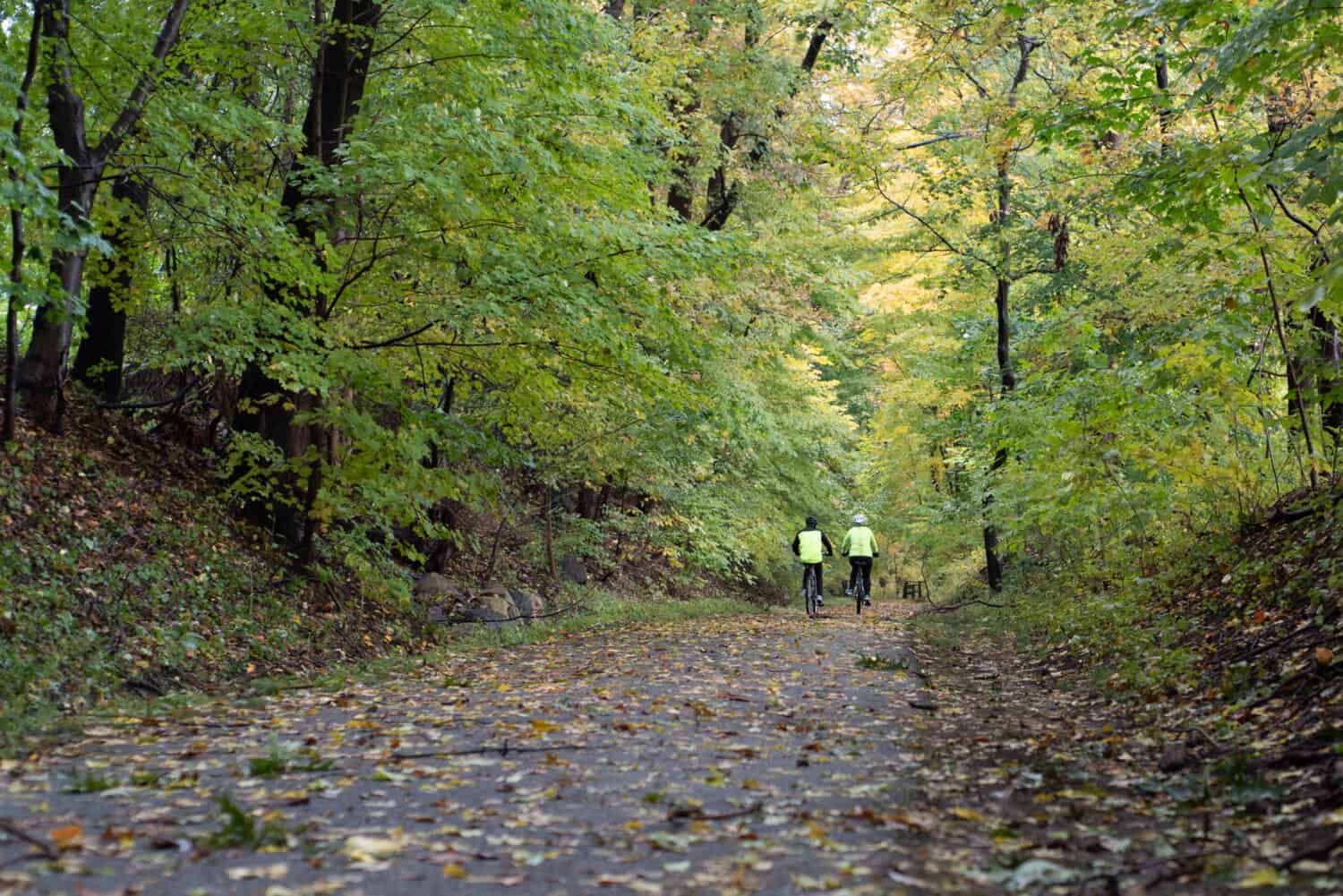 Two cyclists riding on the South County Trail near Ardsley, New York, USA on a wet autumn day.