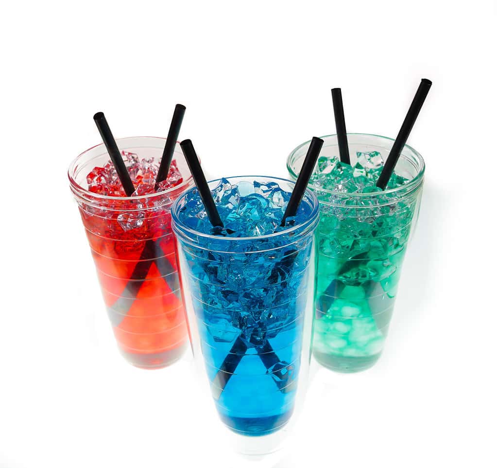 Colorful beverage with two black straws and with ice/condensation isolated against white background.