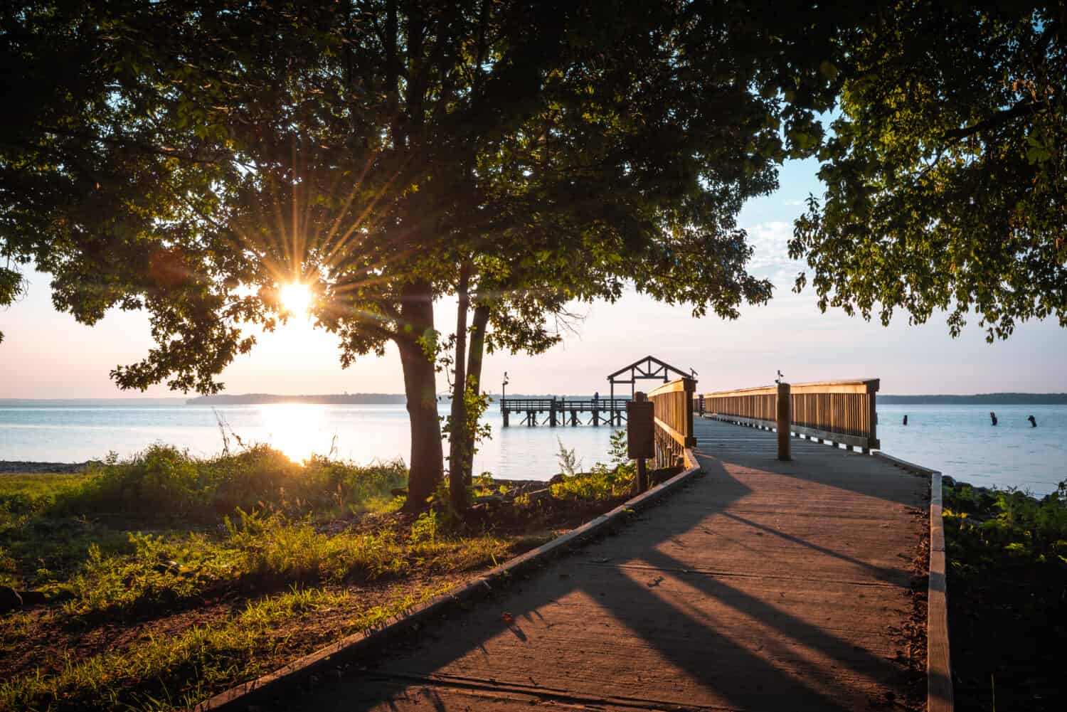 An early morning sun-star shining through the trees at the fishing pier of Leesylvania State Park in Virginia along the shores of the Potomac River.