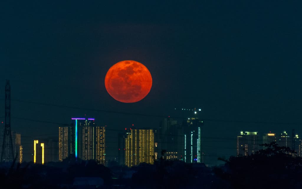 the Hunter's Moon rise over sky scraper ,moment the fullmoon rise with reddish color tone because low the horizon
