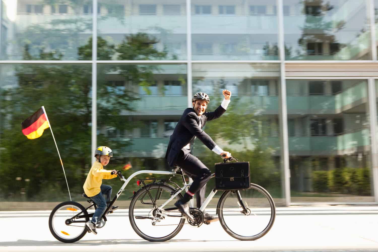 Father and son riding bicycle together on city street