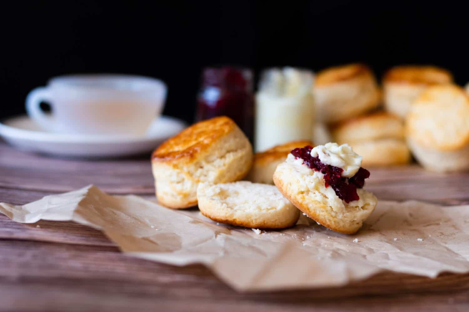 Traditional British Scones with Cream cheese, Cranberry jam and a cup of tea on wooden table black background. 