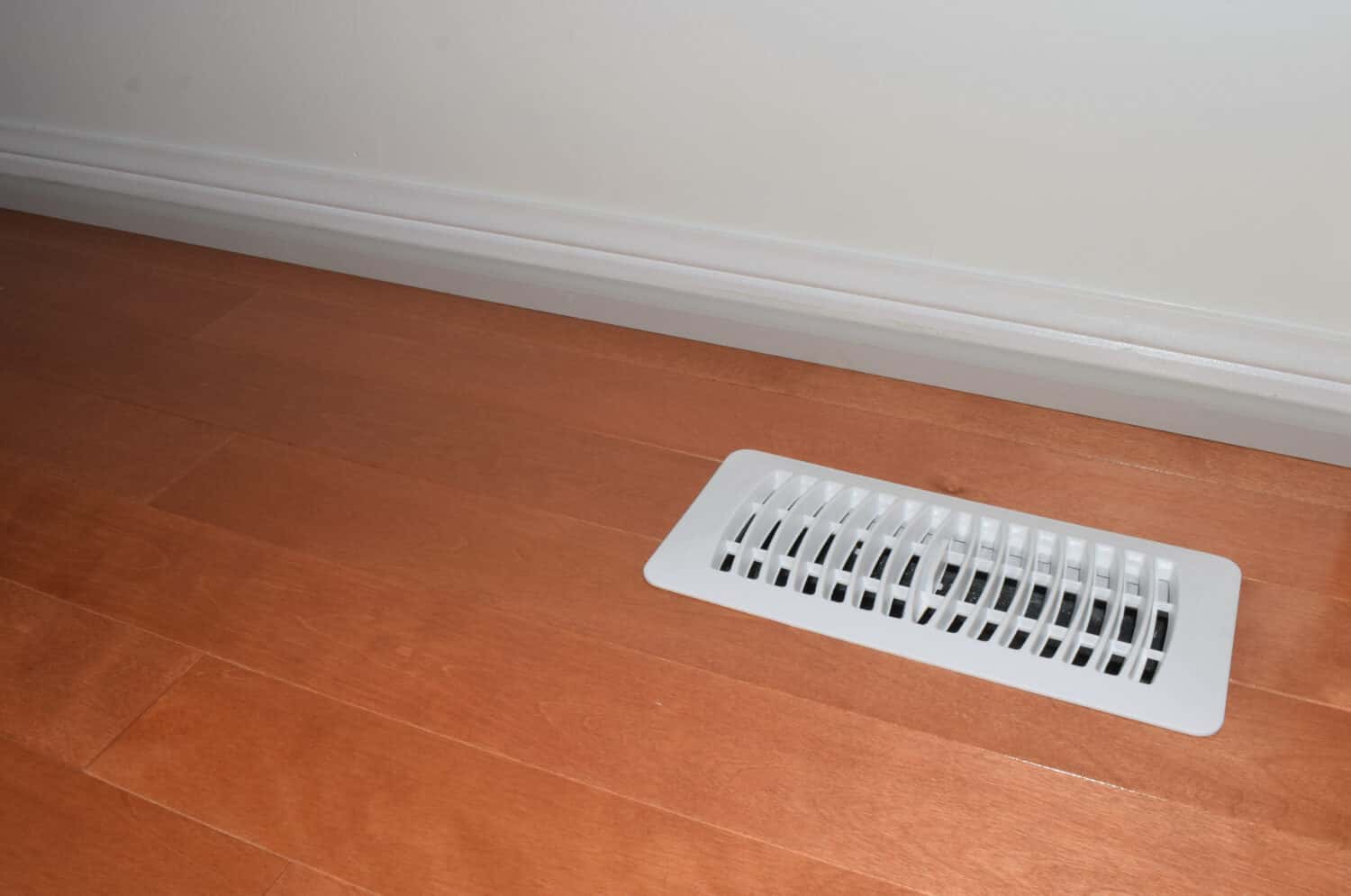 Air vent with with white cover on a hardwood floor