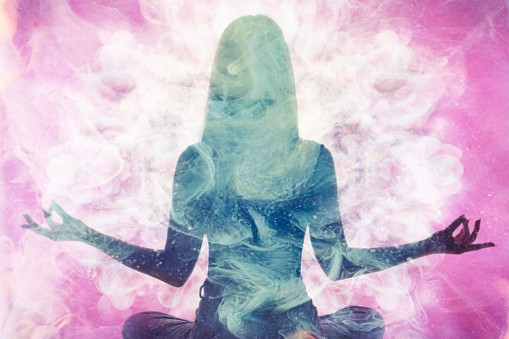 Spiritual practice. Harmony balance. Meditating woman silhouette in pink ethereal smoke double exposition.