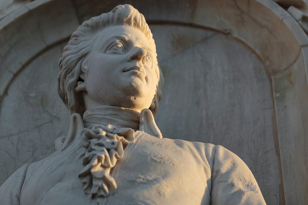 Stone figure of musical genius, composer Wolfgang Amadeus Mozart, in a monument from 1898, closeup horizontal low angle view