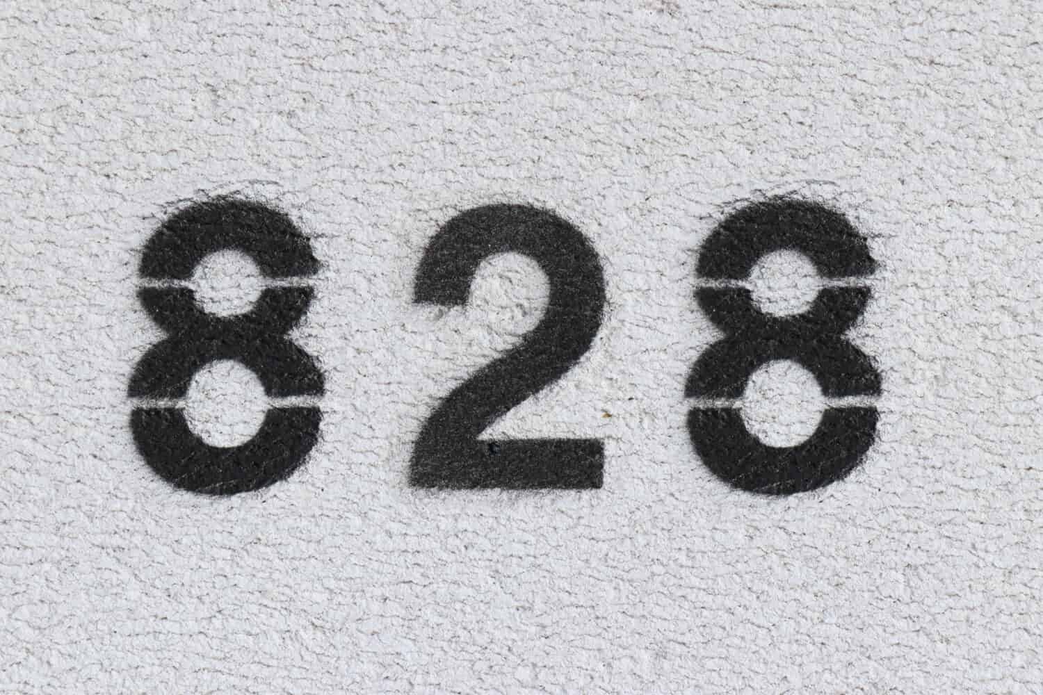 Black Number 828 on the white wall. Spray paint. Number eight hundred and twenty eight.