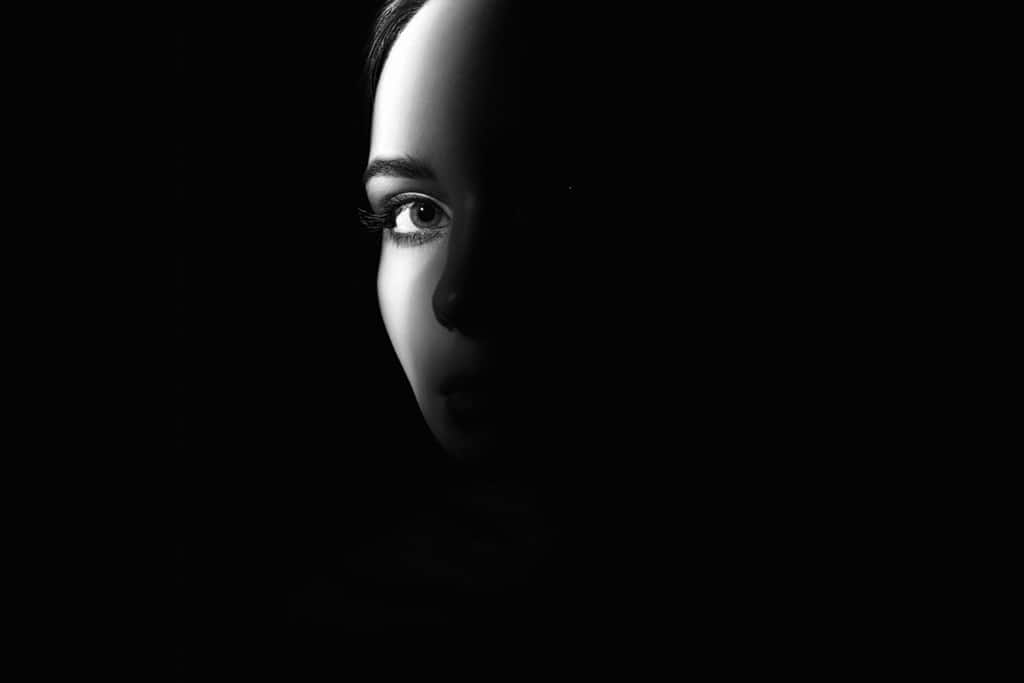 black and white portrait of beautiful girl eye. pretty young woman face part in dark