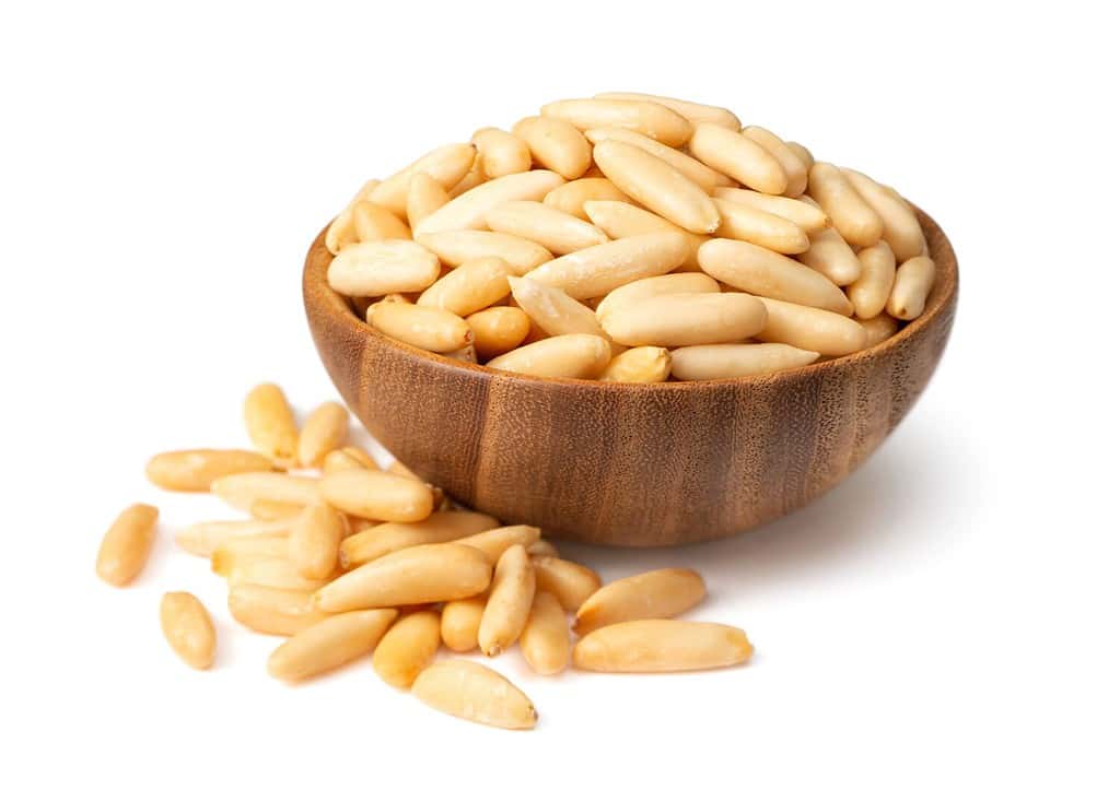 Roasted pine nuts in the wooden bowl. isolated on white background.