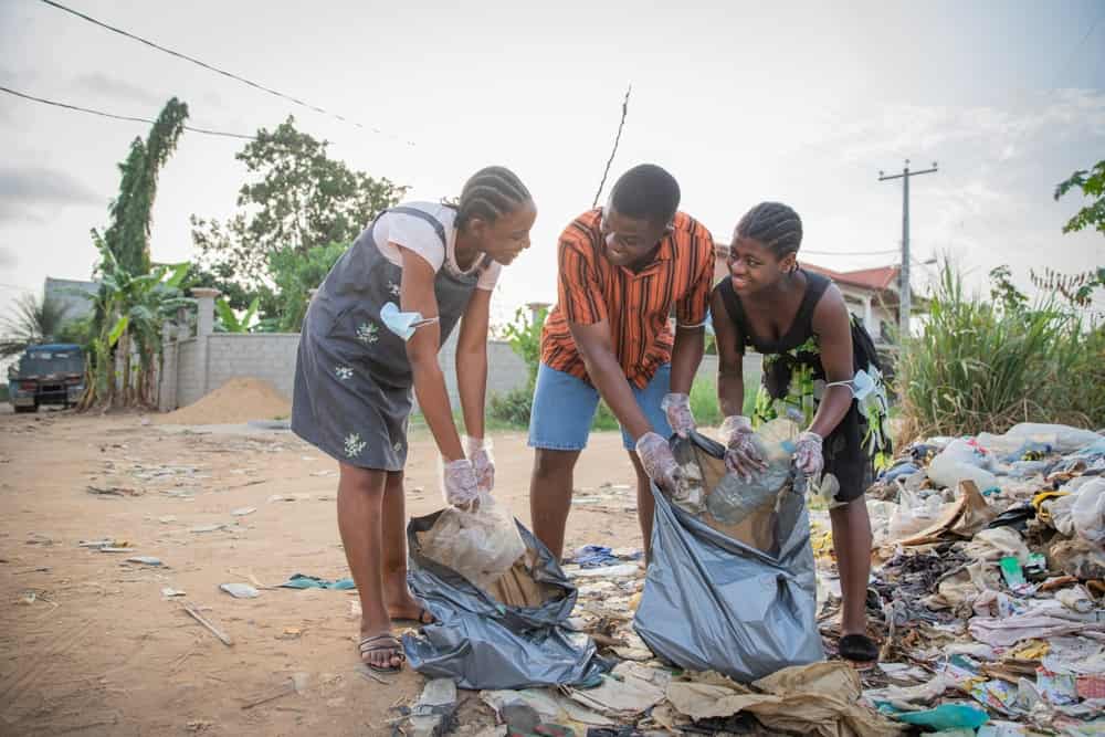Three young people pick up trash that pollutes the environment. Clean world concept.