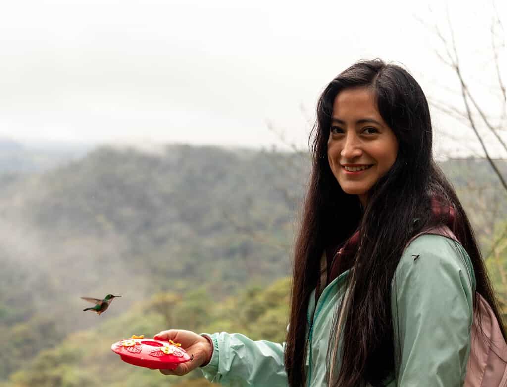 smiling woman with hummingbirds looking at camera
