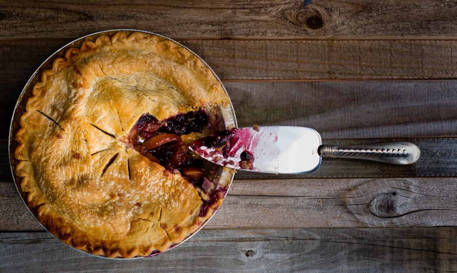Fresh baked blueberry and peach pie sitting on a wooden surface, overhead shot.