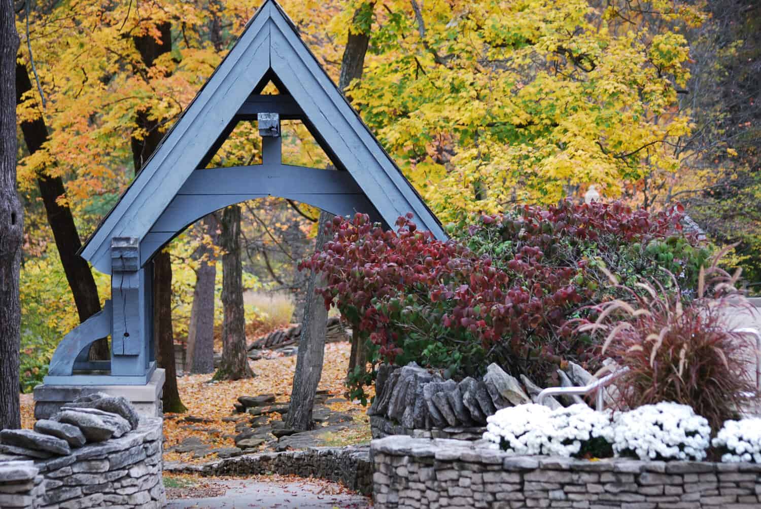 A quaint grey colored wooden archway surrounded by a stone wall at Indiana University in Bloomington, Indiana in the autumn.