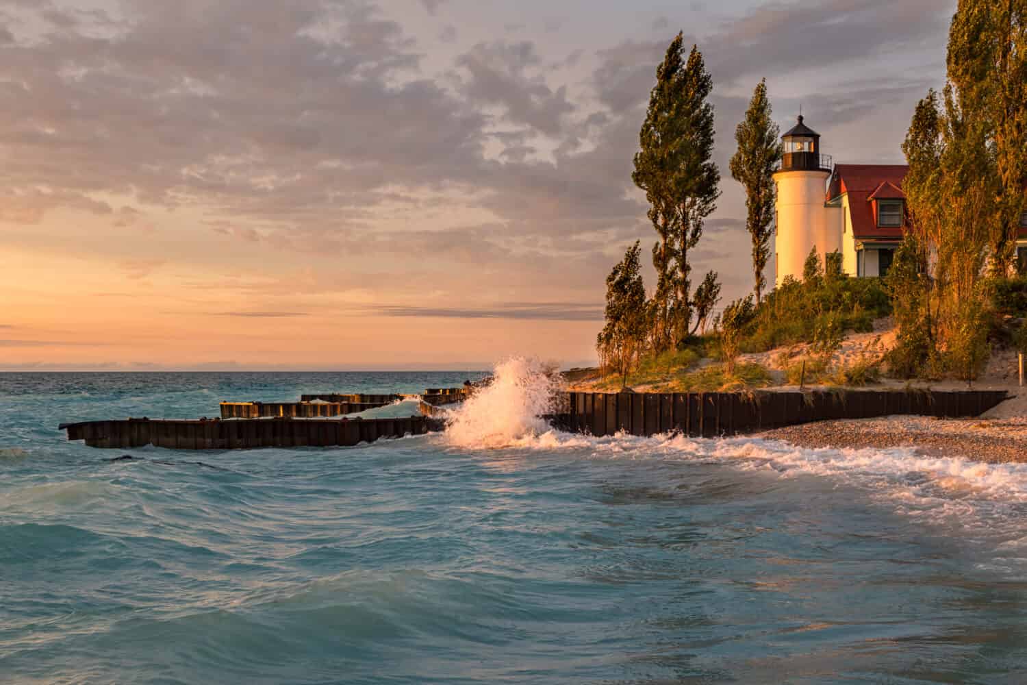 Waves crash along the Lake Michigan shore in front of Point Betsie Lighthouse, during sunset