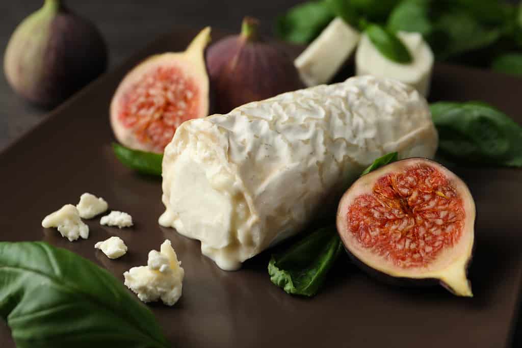 Delicious goat cheese with figs and basil on plate, closeup
