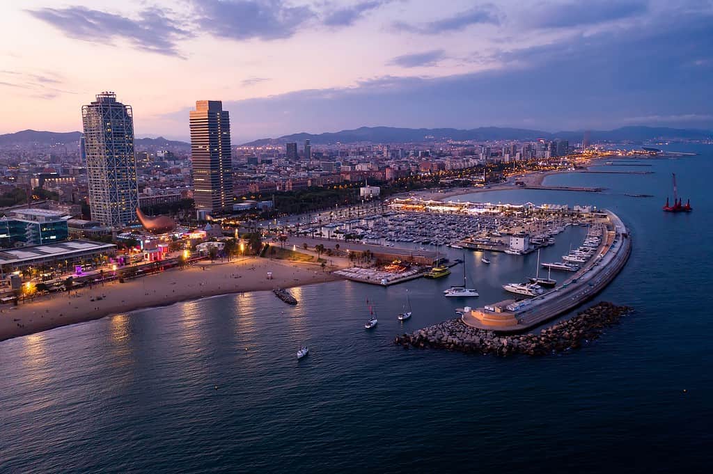 Picturesque evening aerial view of coastal area of Barcelona overlooking Olympic Harbor marina with moored pleasure yachts and modern architecture of waterfront in summer, Spain.