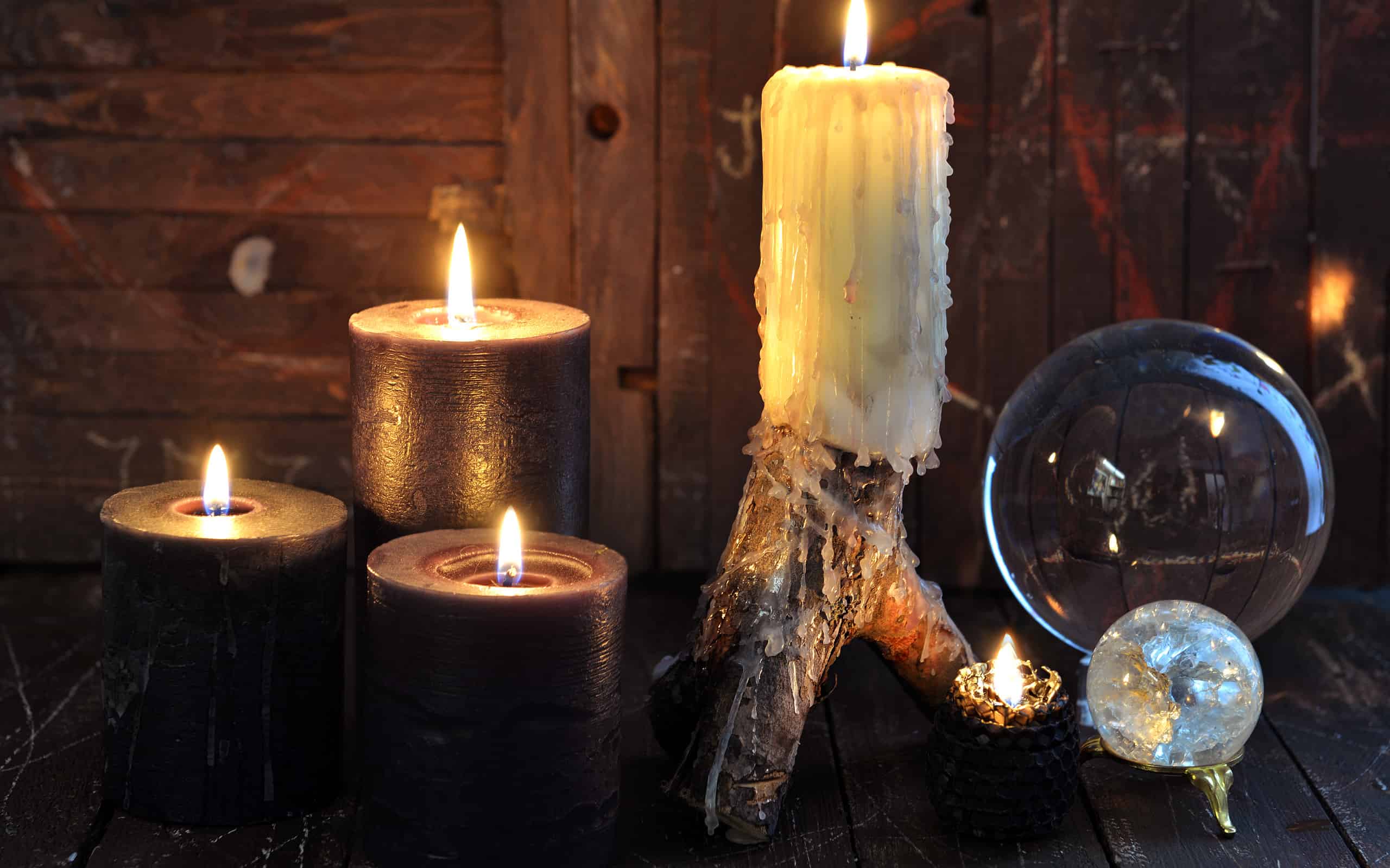 Burning candles and magic crystals on witch wooden table. Esoteric, wicca and occult background with magic objects, fortune telling and divination ritual, Halloween mystic background.