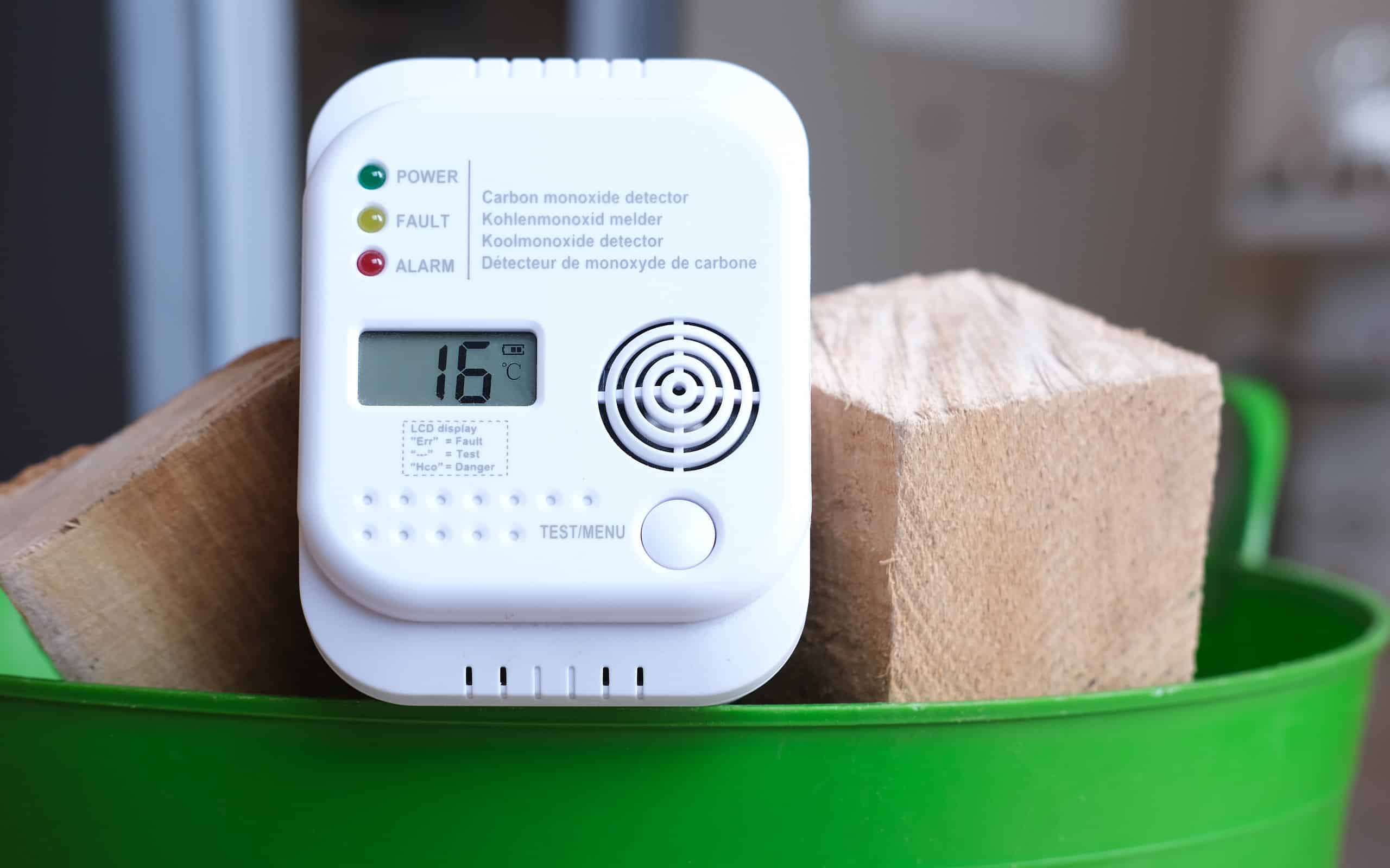Carbon monoxide alarm or CO warning device in a basket of firewood in an apartment in front of a fireplace, selective focus