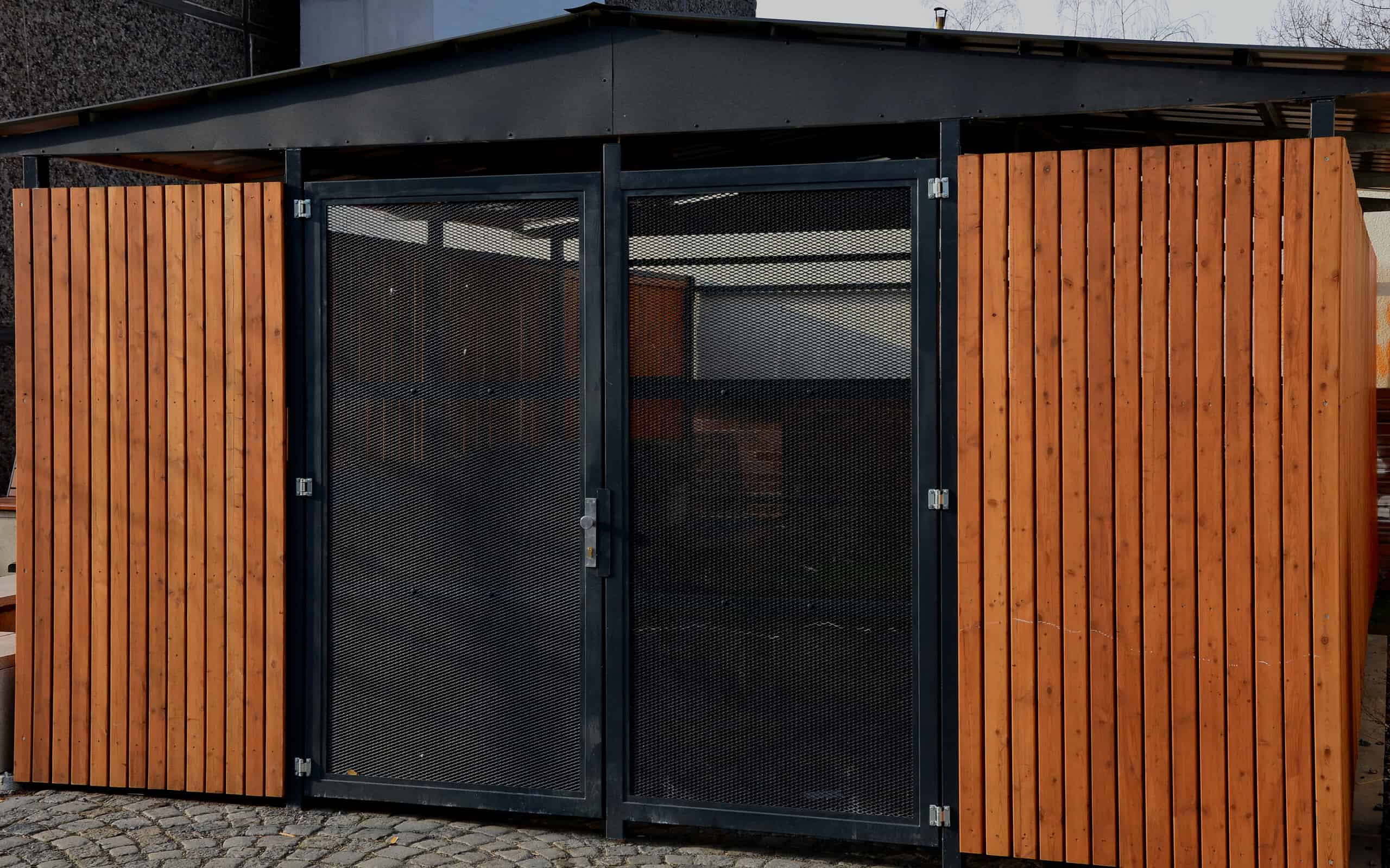 garage with wooden paneling and transparent mesh door. bin storage near the boarding house. protects citizens' property and order in the closed shelter. car parking safe and without snow, cobblestone