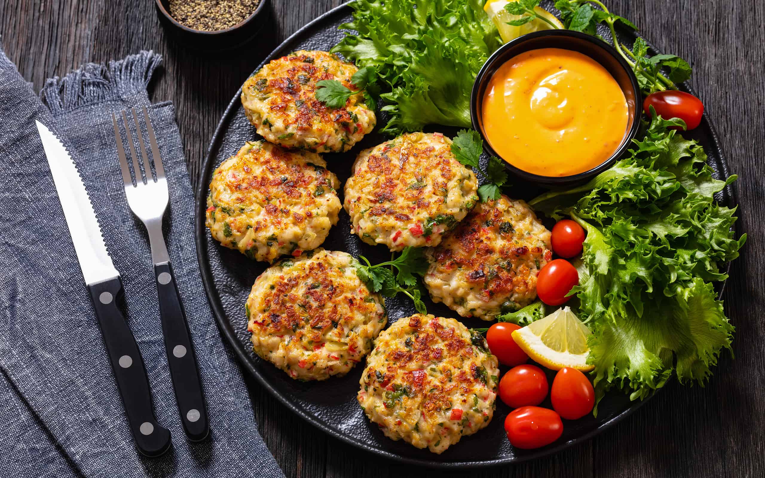 crab cakes with sauce, lettuce, tomatoes, lemon