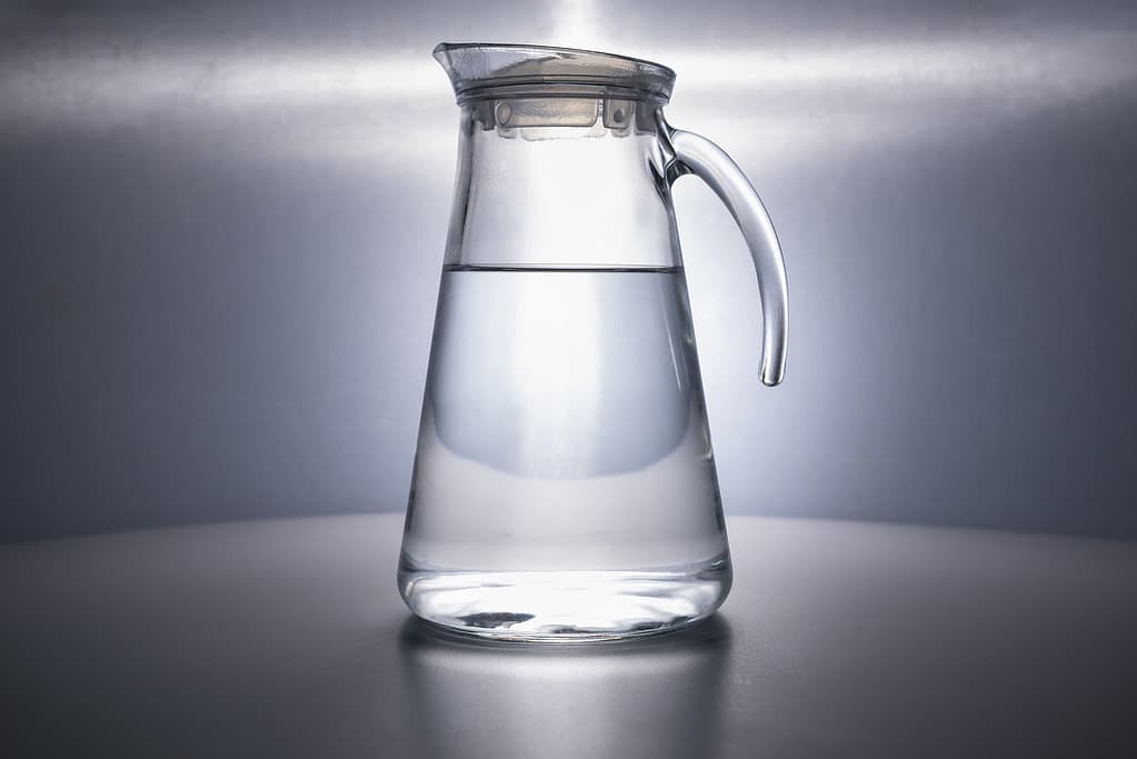 A glass decanter filled with clean drinking water beautifully illuminated on a gray background. Water advertising. Jug. Water is life. Space for text. CopySpace. no people. subject shooting