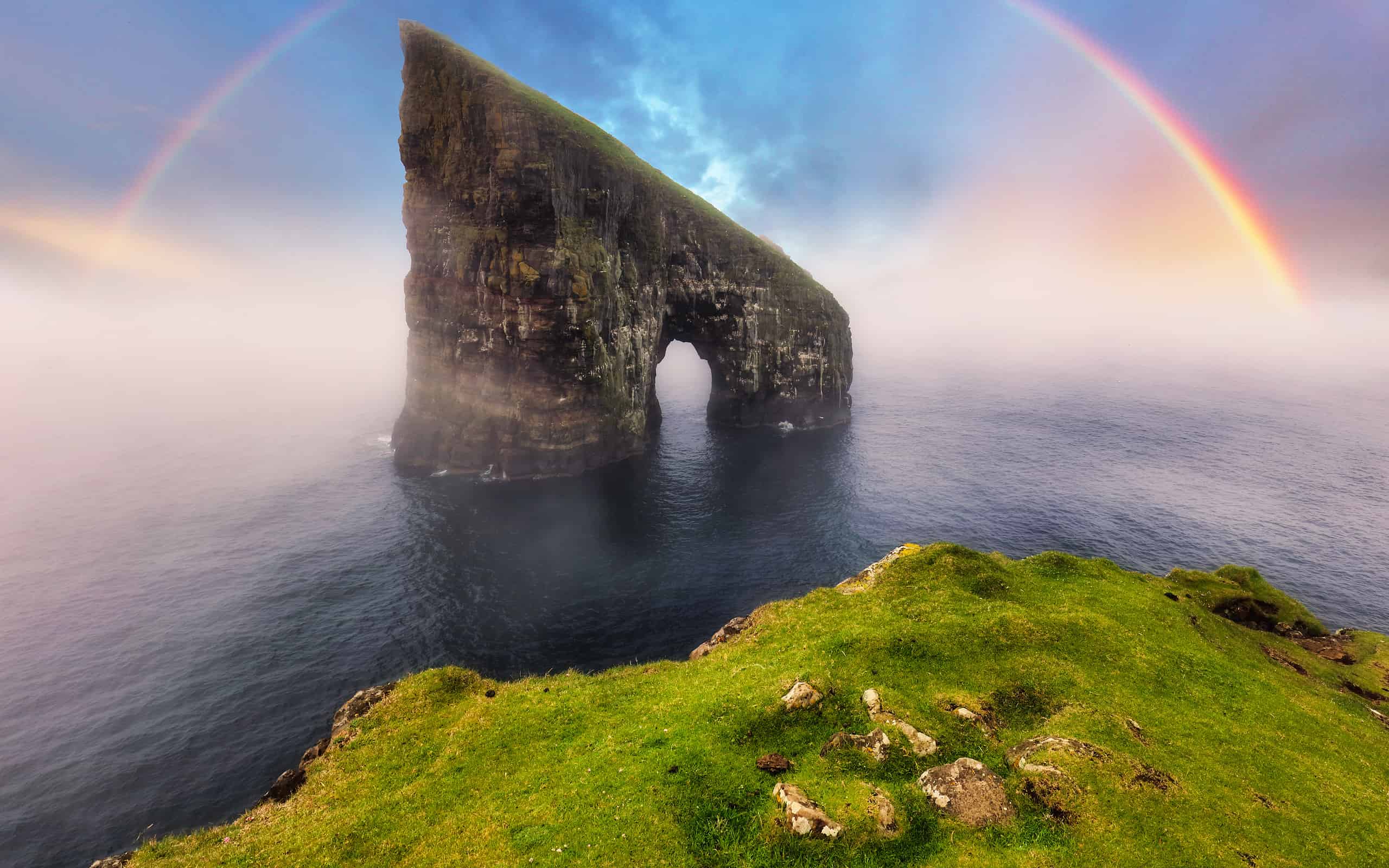 Rainbow over coast cliff in ocean Drangarnir in Faroe island. Sunset landscape