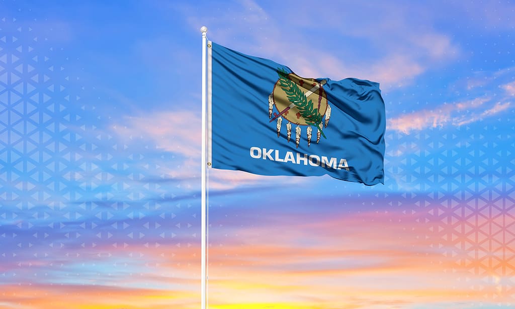 Oklahoma state flag flowing in the breeze. Sunset behind the flag.