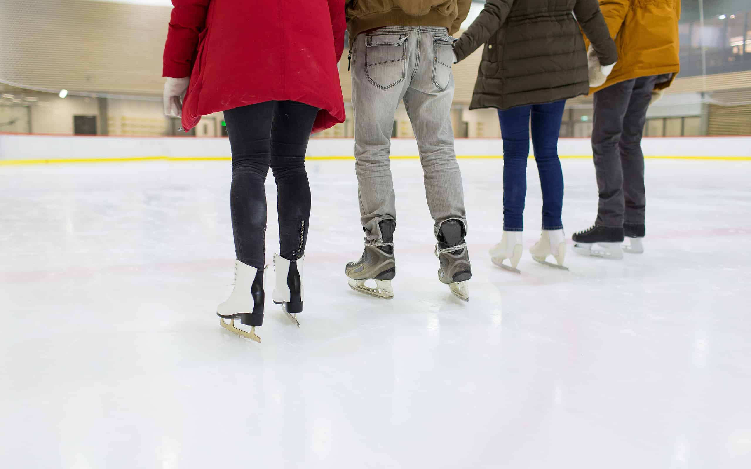 close up of happy friends skating on ice rink