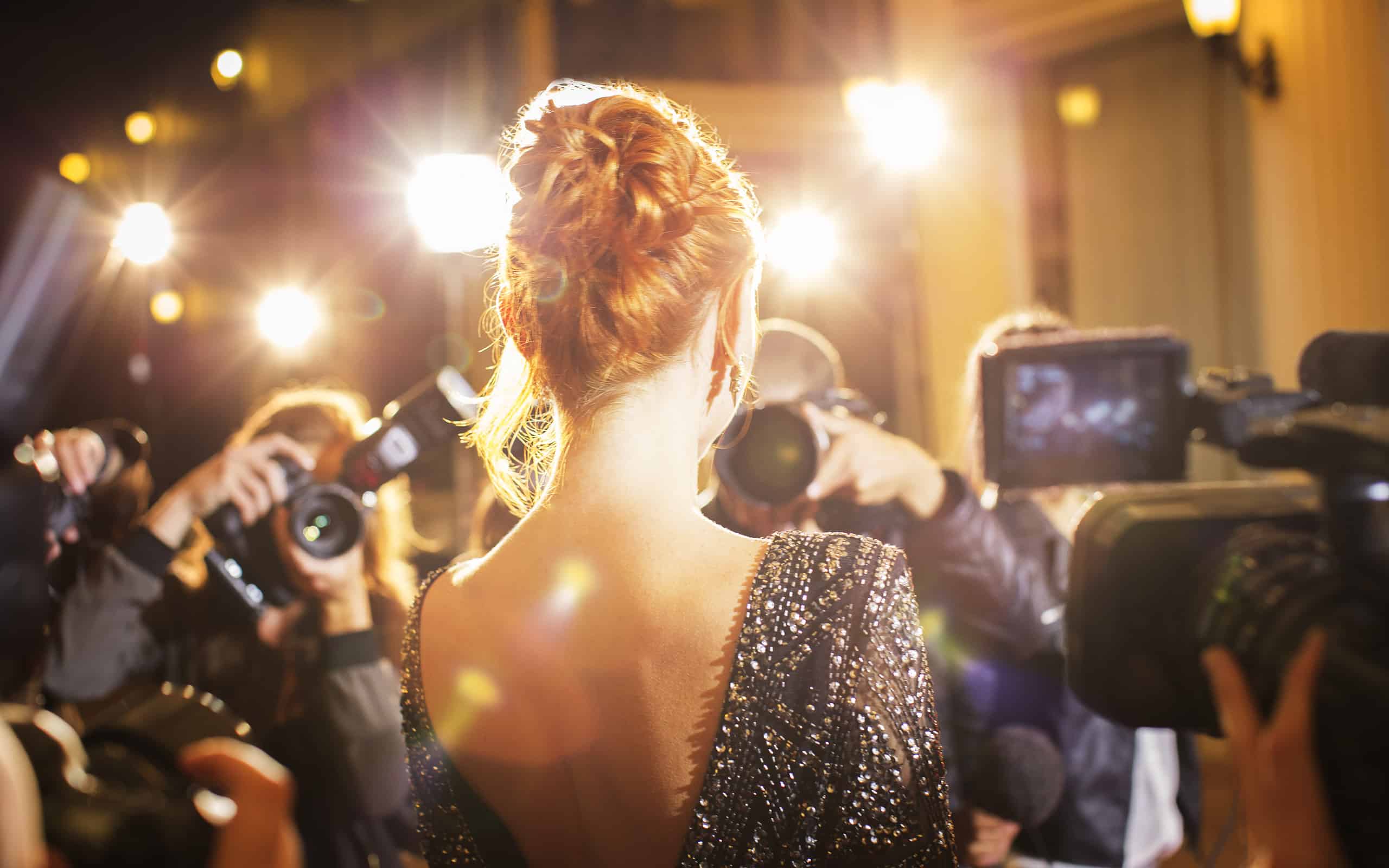 Celebrity being photographed by paparazzi photographers at event