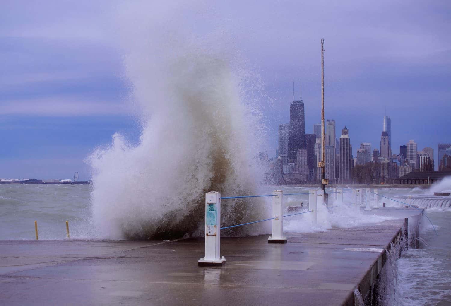 Giant waves crash over a harbor of Lake Michigan, with downtown Chicago in the background. 