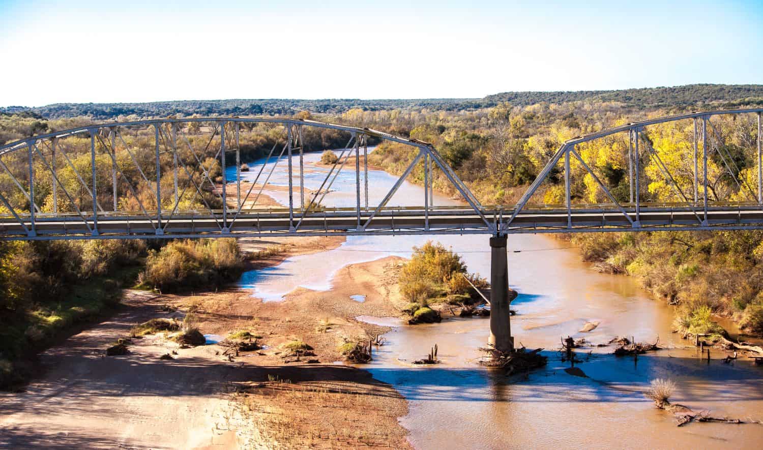 Bridge over the red river in central Texas.  The Red River, or sometimes the Red River of the South, is a major tributary of the Mississippi