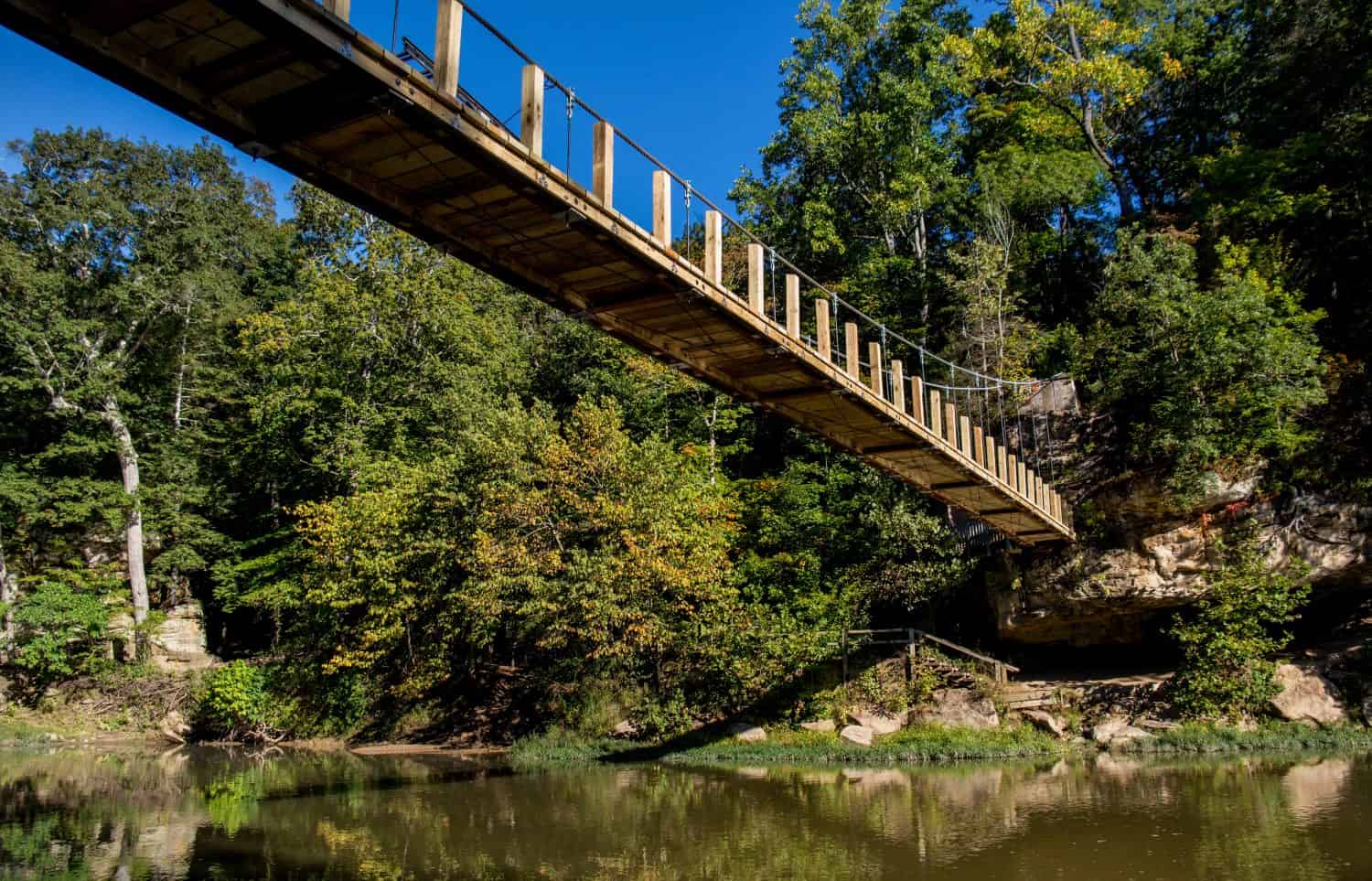 A suspension bridge spans sugar creek,  at turkey run state park in  marshall Indiana
