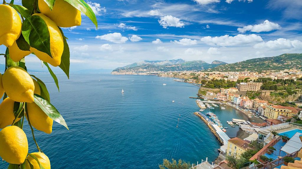 Daylight aerial view of cliff coastline Sorrento and Gulf of Naples in Southern Italy. Ripe yellow lemons in foreground. In Sorrento lemons are used in production of limoncello.