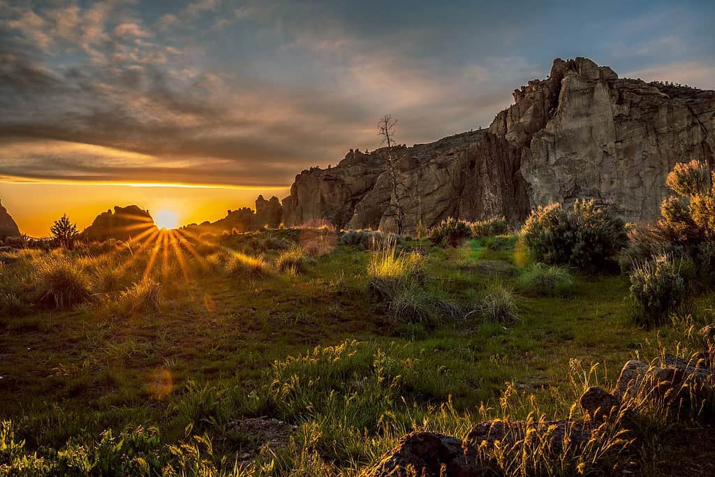 Sun setting over a hilly and mountainous landscape at Smith Rock State Park in Redmond, Oregon, United States.