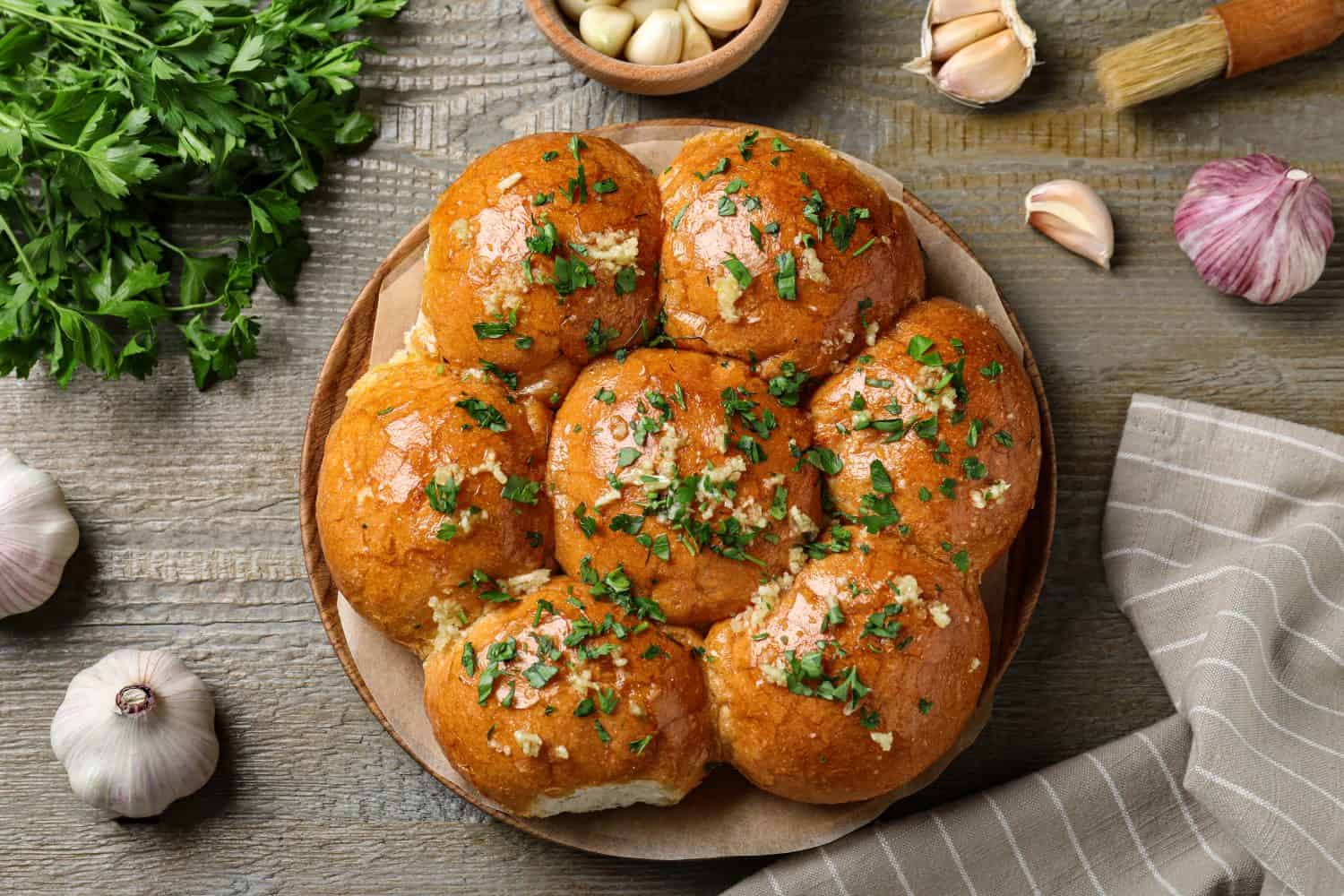 Traditional Ukrainian garlic bread (Pampushky) on wooden table, flat lay