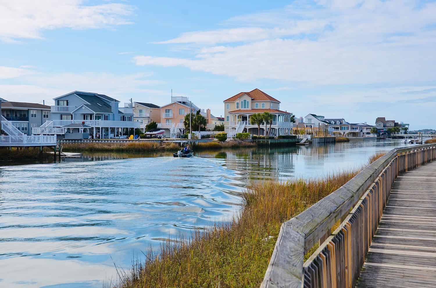 Scenic river view and waterfront houses, in North Myrtle Beach, South Carolina, USA. The wooden boardwalk is located in the Heritage Shores Nature Preserve, a walking trail through the salt marsh.