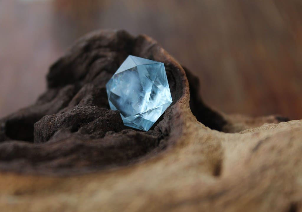 Faceted blue topaz on a gnarled wood background
