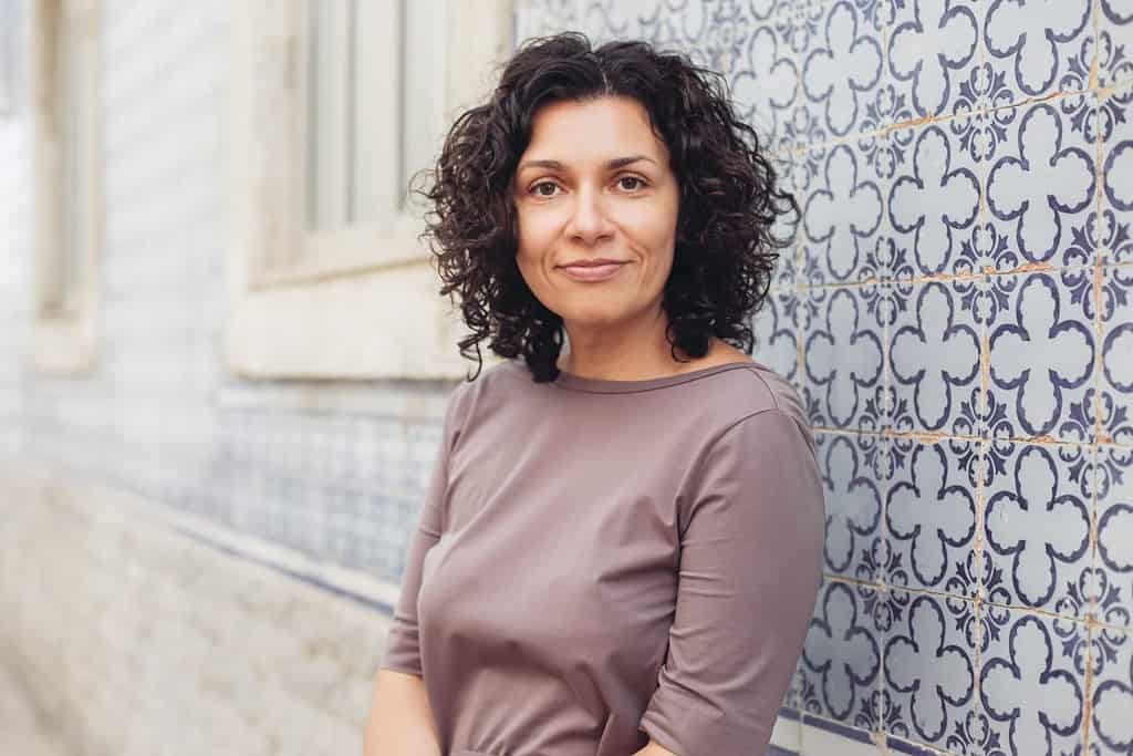 A woman with curly hair in Portugal. A wall with traditional Portuguese tiles