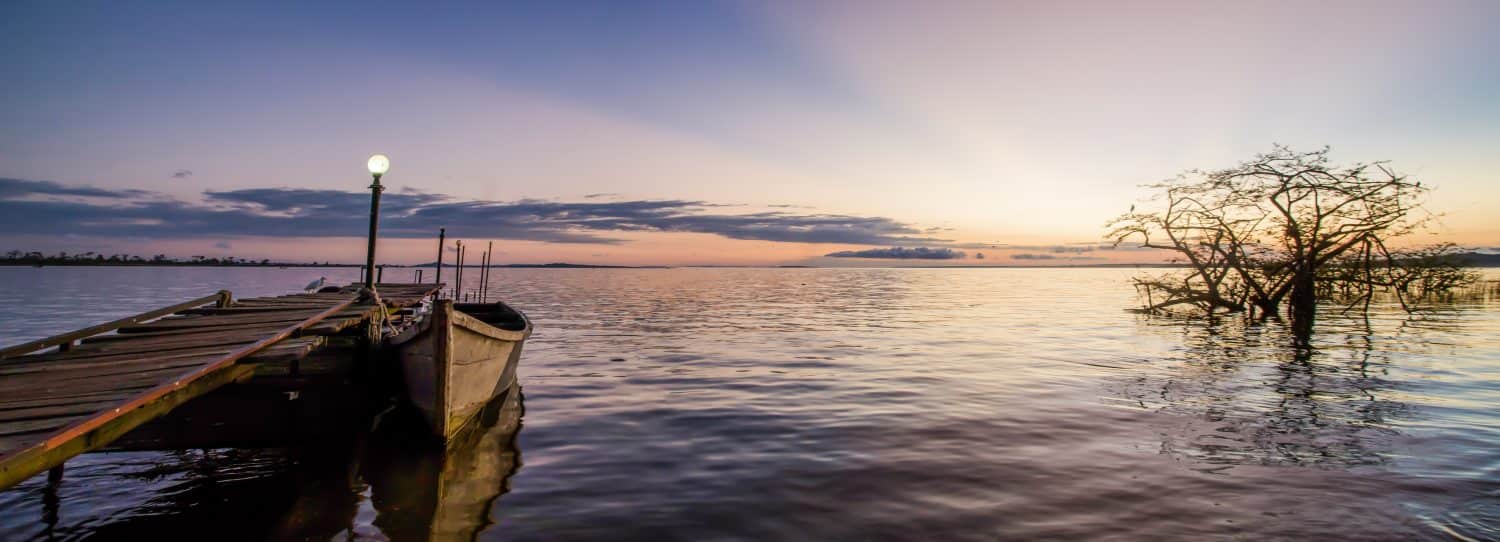 Named after Queen Victoria, Lake Victoria is the largest tropical fresh water lake in the world. Taken at sunrise this photo is looking out onto the lake with Islands in the distance and a boat.